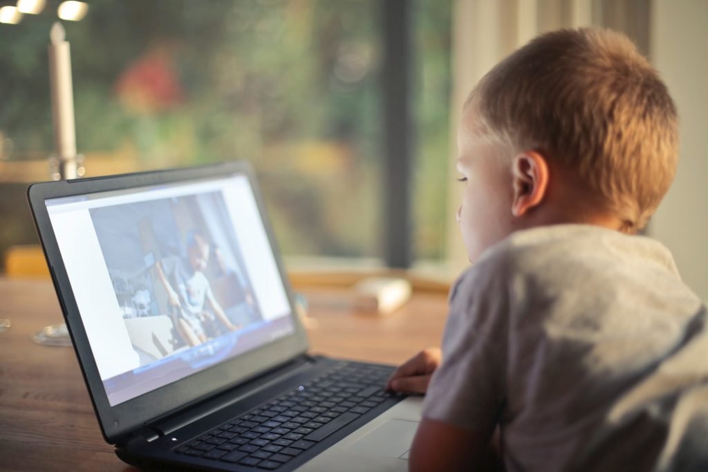Boy watching video on computer - Ways to Be an Awesome Long Distance Grandparent - Adventures in NanaLand
