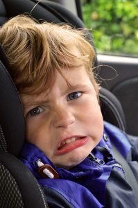 Grandchild with angry face sitting in carseat