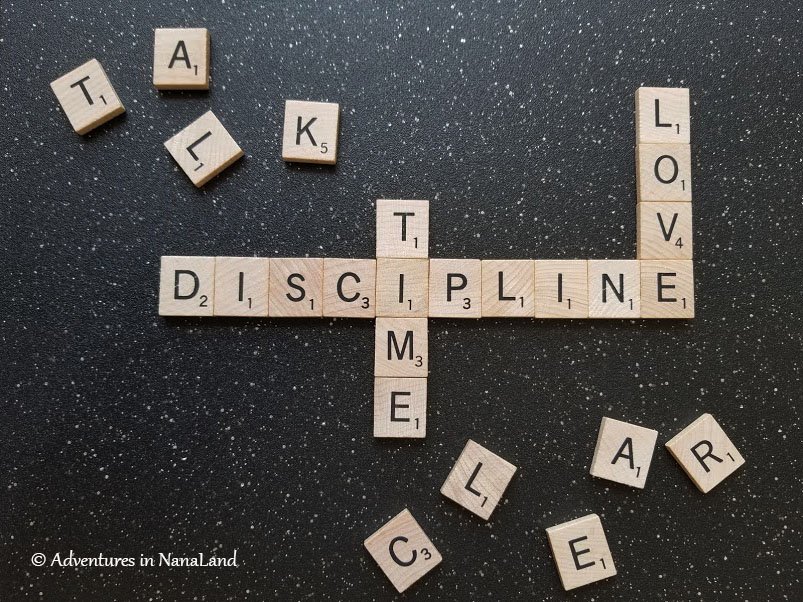 The words discipline love and time spelled out with scrabble tiles