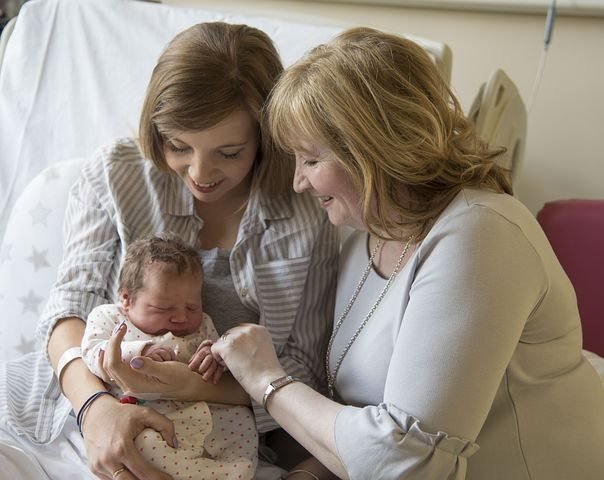 Three generations of women - newborn baby, mom and grandma in hospital room