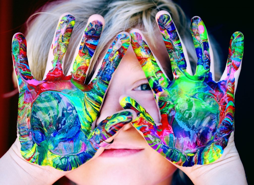 boy with colorful paint all over hands in front of his face - Adventures in NanaLand - Things to do with grandkids