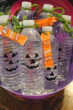 Water bottles with pumpkin faces drawn on the front with a packet of orange-flavored drink attached- Non-candy Halloween treats - Adventures in NanaLand
